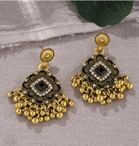 Detail view of retro flower earrings with black stones and gold beaded tassels