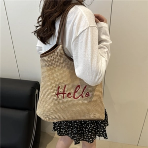 Straw tote bag with brown faux leather trim and red embroidered Hello lettering