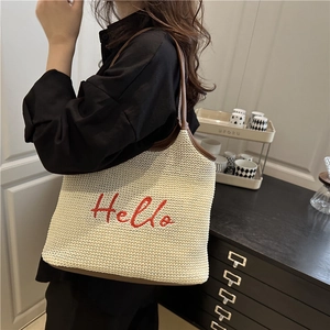 Chic woven tote bag with red Hello embroidery and brown leather trim on woman shoulder