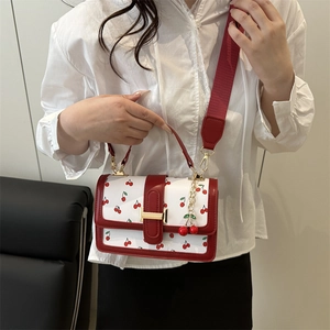 Sac bandoulière blanc à motifs cerises, poignées en cuir rouge et boucles dorées