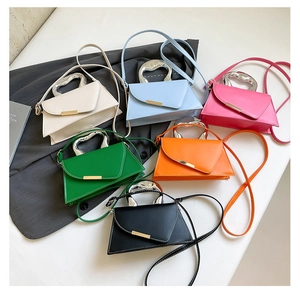 Detail of colorful trapezoid handbags with fluid metal handles and asymmetric flap design