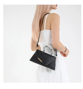 Detail of black minimalist bag with unique silver metal handle and envelope flap