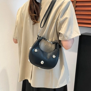 Black hobo shoulder bag with silver studs and adjustable strap on a female model