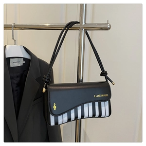 Detail view of piano key pattern and gold I LIKE MUSIC lettering on black crossbody bag