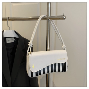 Detail of white leather shoulder bag featuring a wave flap and piano key pattern