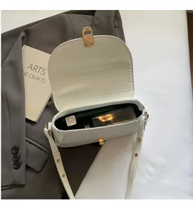 Détail du compartiment intérieur spacieux et du fermoir doré du sac besace blanc cassé