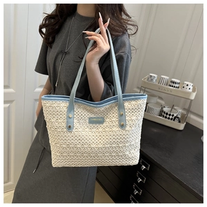 Détail du cabas en paille tissée blanche avec lanières en cuir bleu clair et étiquette de marque