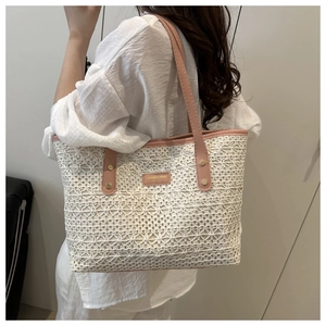 Detail of white hollow woven tote bag featuring pink leather handles and branded patch