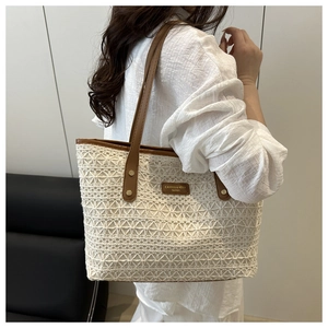 Close-up of hollow lace weave texture and leather strap on this summer straw tote bag
