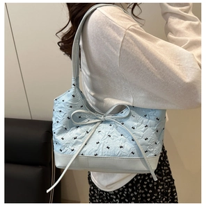 Dettaglio della borsa tote azzurra con trama 3D, ricamo a fiocco e tracolla abbinata