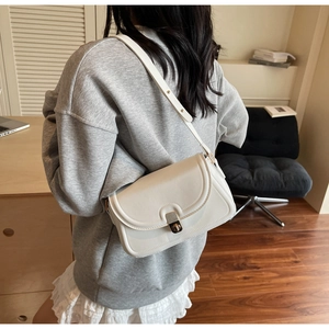 Mannequin avec sac enveloppe blanc cassé, fermoir doré et bandoulière réglable