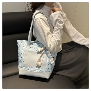 Detail of light blue quilted tote bag with floral silk scarf bow and black bird embroidery