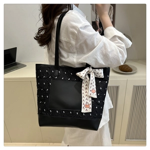 Detail of black quilted tote bag with decorative patterned silk scarf and side pocket