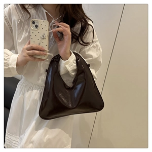Detail of dark patent leather handbag with pleated handle and vintage glossy finish