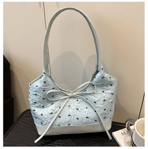 Dettaglio della borsa tote blu con motivi a fiocco in rilievo e sottili spalline lunghe
