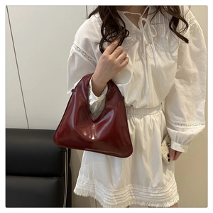 Close-up of deep burgundy wax leather handbag with asymmetrical triangle design and chain