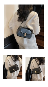Détail d'un sac bandoulière vintage en cuir noir avec un fermoir ovale doré poli