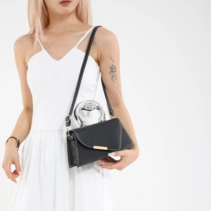 Trapezoid black leather bag with silver metal handle and white stitching detail