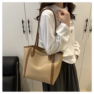Detail of the large beige and brown tote bag showing reinforced stitching on shoulder straps