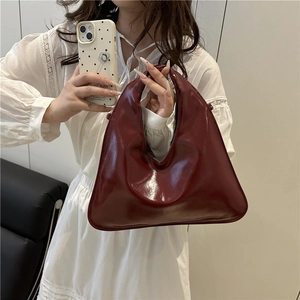 Deep red patent leather underarm bag with a unique inverted triangular silhouette