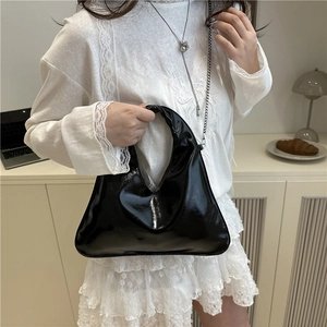 Modern black patent leather hobo bag with a mirror finish shown on a fashion model
