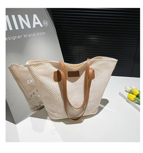 Detailed texture of beige woven straw tote bag with brown leather shoulder straps