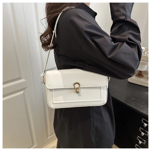 Detailed close-up of a white leather bag with a golden U-shaped clasp worn by a model