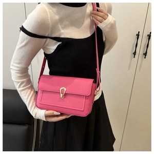 Detail of hot pink crossbody bag showing the golden horseshoe buckle and leather texture