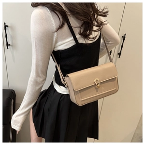 Detail of beige leather bag featuring a teardrop gold clasp and minimalist shoulder strap