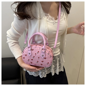 Detail der rosa Handtasche mit Kirschmuster, Silberbeschlägen und Reißverschluss
