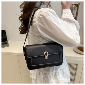 Detail of black pebbled leather shoulder bag with a gold horseshoe buckle closure