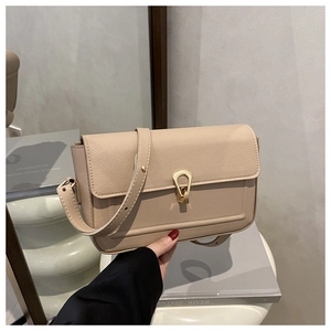 Detail of apricot pebbled leather shoulder bag featuring a gold horseshoe buckle and strap