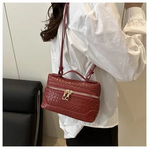 Detail of burgundy woven texture box bag with gold double zippers and top handle