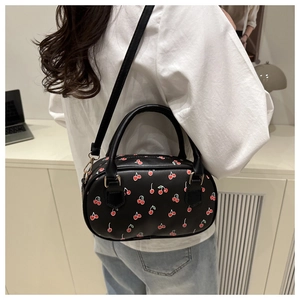 Detail of cherry print boston bag with leather handles and gold metal attachments