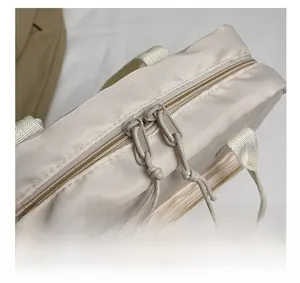 Detail showing two-way zipper closure with cord pulls on cream fabric tote bag