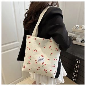 Detailed texture of white corduroy tote bag with cherry print and wide shoulder strap