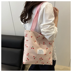 Detail view of pink corduroy tote bag with cherry patterns and soft fabric strap