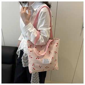 Borsa tote in velluto rosa con stampa di ciliegie e tracolla lunga indossata da un modello