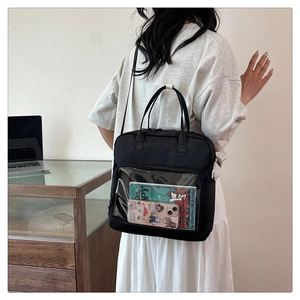 Detail of black canvas tote with clear PVC pocket showing storage for books and phones