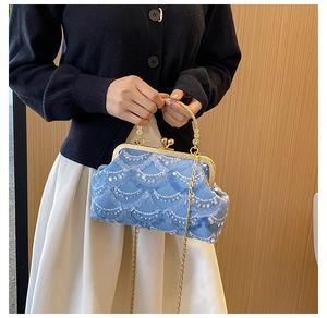 Detail of light blue satin evening bag with wave patterns of white sequins and gold clasp