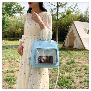 Detail of light blue Japanese style backpack with a clear PVC front pocket in outdoor setting