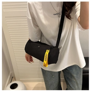Seitenansicht der schwarzen Zylindertasche mit kontrastierendem gelbem Logogurt