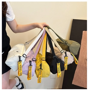 Gros plan de sacs cylindriques en nylon coloré avec breloques ruban à slogan jaune