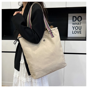 Detail der minimalistischen beige Tote-Bag mit dreifarbig gewebtem Schultergurt in Rot-Blau