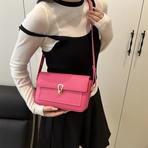 Retro fuchsia leather shoulder bag with gold horseshoe lock shown on model