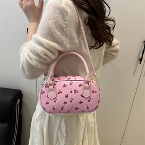 Pink cherry print barrel bag shown on a model as a shoulder bag and handbag