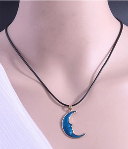 Detail of blue crescent moon pendant necklace with star on a black cord strap
