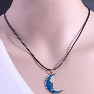 Chic moon face pendant necklace with blue enamel and gold stars on a black cord