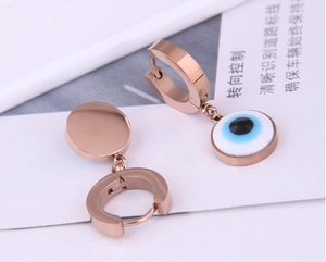 Détail de boucles d'oreilles œil protecteur or rose avec pendentif disque émaillé