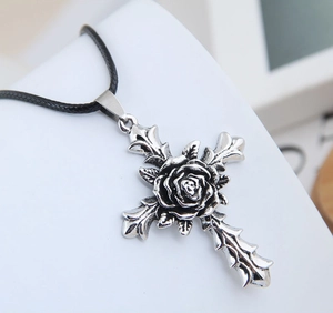 Macro shot of retro silver cross pendant with 3D rose detail on black cord